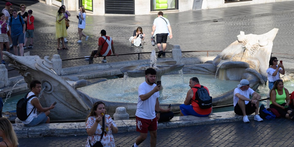 Los turistas se relajan y toman fotos junto a la Fuente de la Barcaza en Roma.