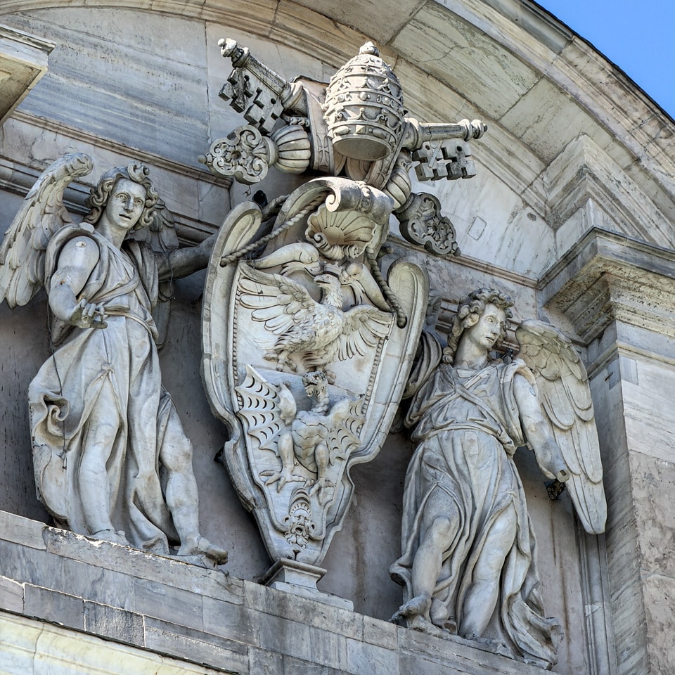 Escudo de la familia Borghese con tiara papal, llaves cruzadas, águila y dragón, flanqueado por ángeles de mármol en la fuente del Acqua Paola, Roma
