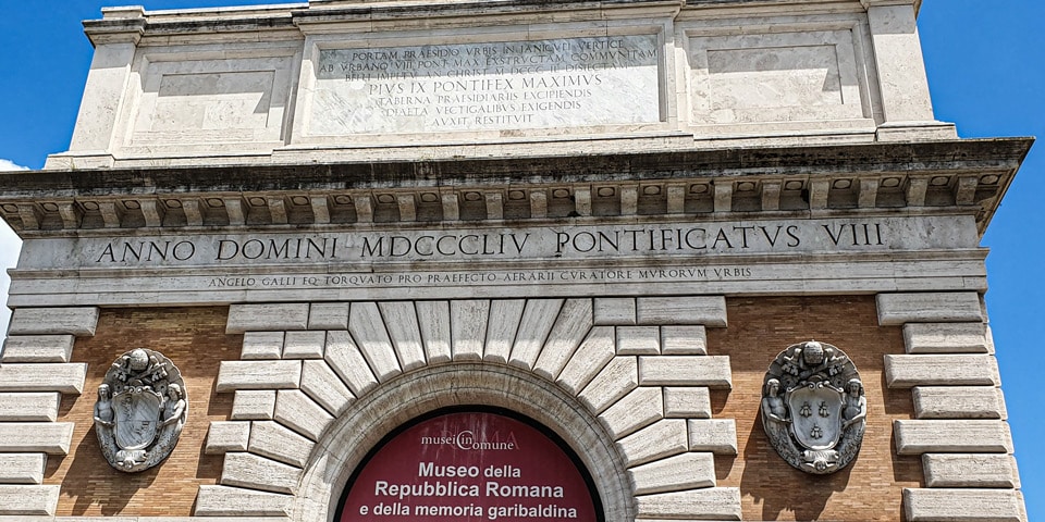 Inscripciones latinas de reconstrucción y escudos de los papas Pío IX y Urbano VIII sobre Porta San Pancrazio en Roma